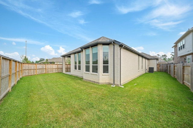 rear view of property featuring a fenced backyard, a yard, and cooling unit