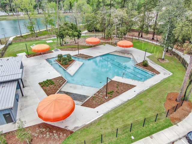 community pool featuring a patio, a water view, fence, and a yard