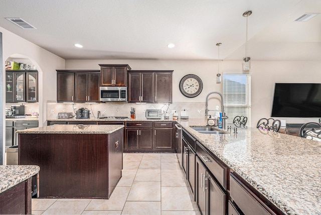 23414 Bracino Lake Dr, Katy, TX 77493 - kitchen with light stone countertops, appliances with stainless steel finishes, a sink, arched walkways, and visible vents