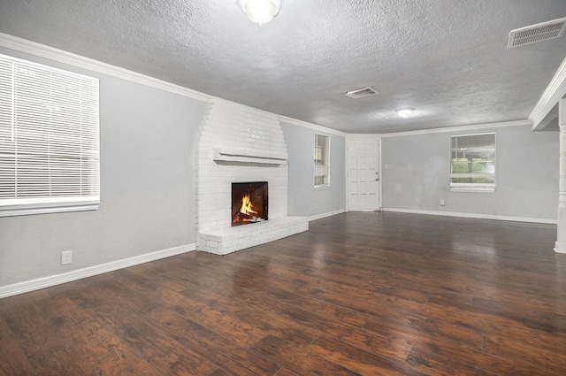 unfurnished living room featuring visible vents, a textured ceiling, wood finished floors, and a fireplace
