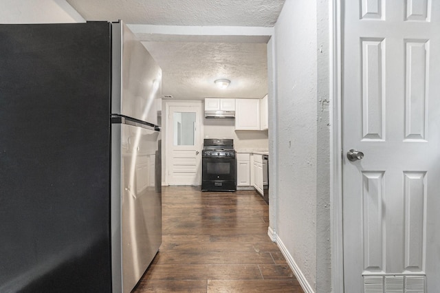 hallway featuring dark wood-style flooring, a textured ceiling, a textured wall, and baseboards