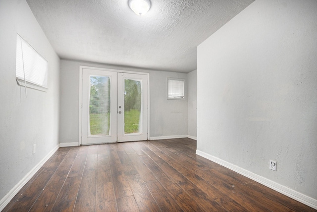 spare room featuring french doors, a textured ceiling, baseboards, and hardwood / wood-style flooring