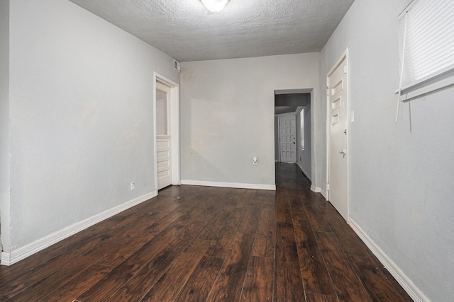 unfurnished room featuring wood-type flooring, a textured ceiling, and baseboards