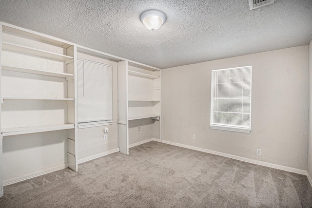 unfurnished bedroom featuring carpet floors, baseboards, a textured ceiling, and visible vents