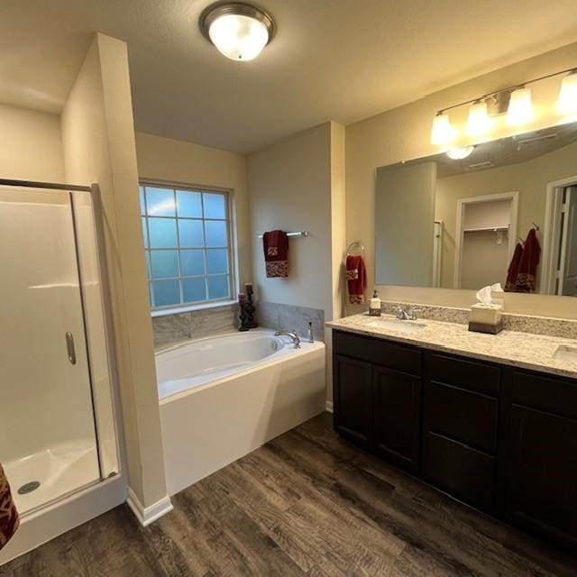 full bathroom with a sink, a shower stall, wood finished floors, and a garden tub