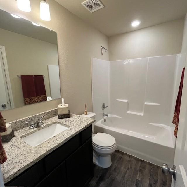 bathroom featuring visible vents, vanity, tub / shower combination, wood finished floors, and toilet