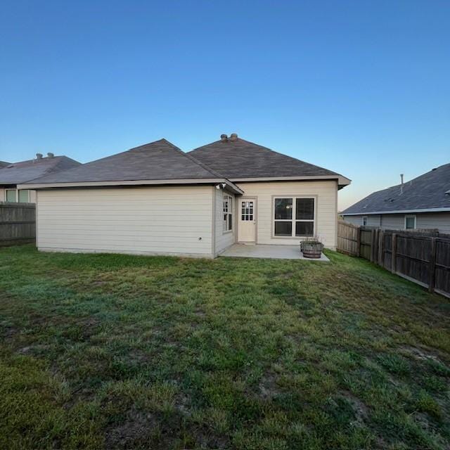 back of property with a fenced backyard, a patio, and a yard