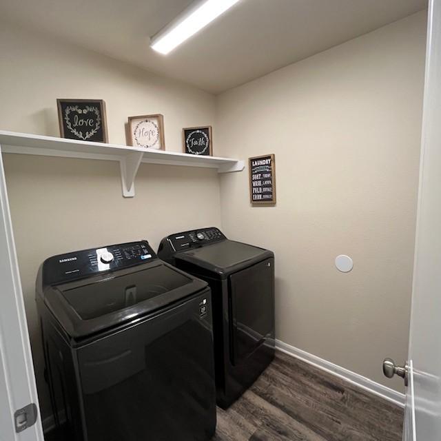 clothes washing area with baseboards, laundry area, dark wood-style floors, and washer and dryer