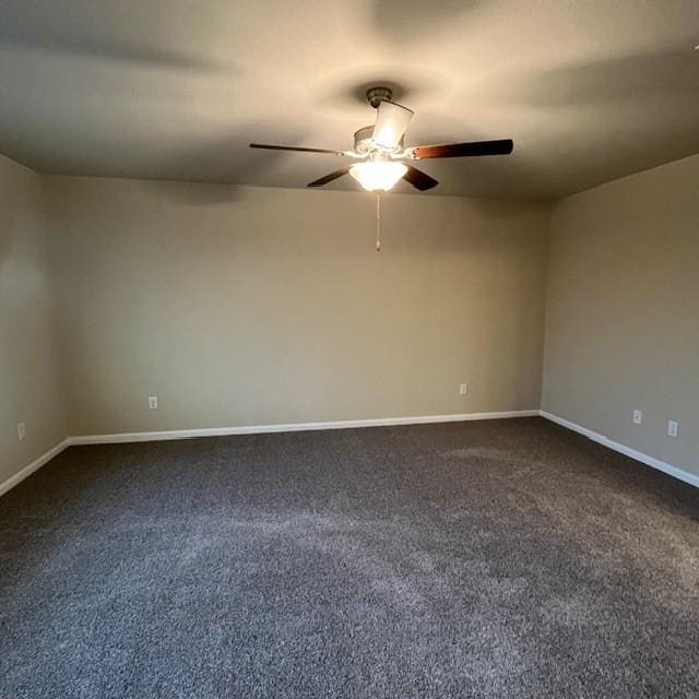 spare room with baseboards, a ceiling fan, and dark carpet