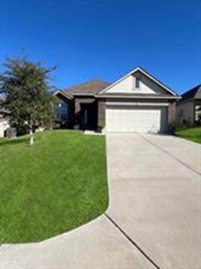 ranch-style house with an attached garage, concrete driveway, and a front yard