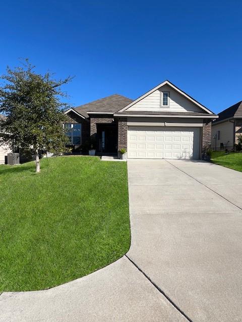 ranch-style house featuring an attached garage, brick siding, a front yard, central air condition unit, and driveway