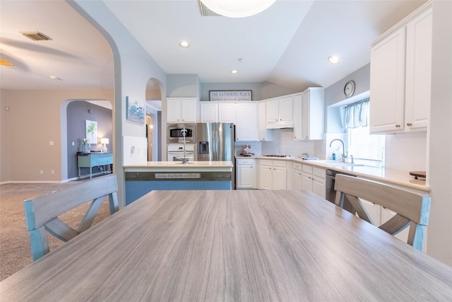 834 Arbor Pne, Tomball, TX 77375 - kitchen with stainless steel appliances, arched walkways, decorative backsplash, white cabinetry, and lofted ceiling