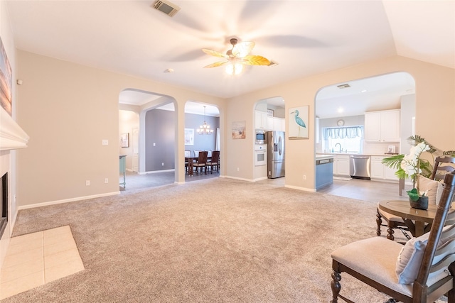 834 Arbor Pne, Tomball, TX 77375 - living room featuring arched walkways, a ceiling fan, light colored carpet, a chandelier, and a fireplace with flush hearth