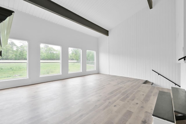 unfurnished living room featuring vaulted ceiling with beams and wood finished floors