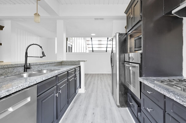 kitchen featuring visible vents, beam ceiling, a sink, light wood finished floors, and stainless steel appliances