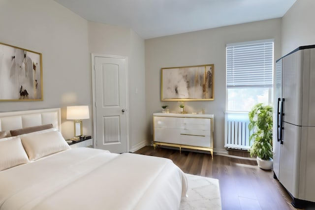 bedroom with dark wood-style flooring, baseboards, and radiator