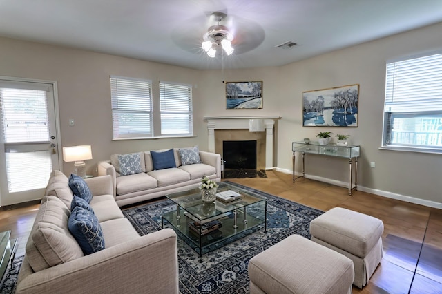 living room featuring visible vents, ceiling fan, a healthy amount of sunlight, and a premium fireplace