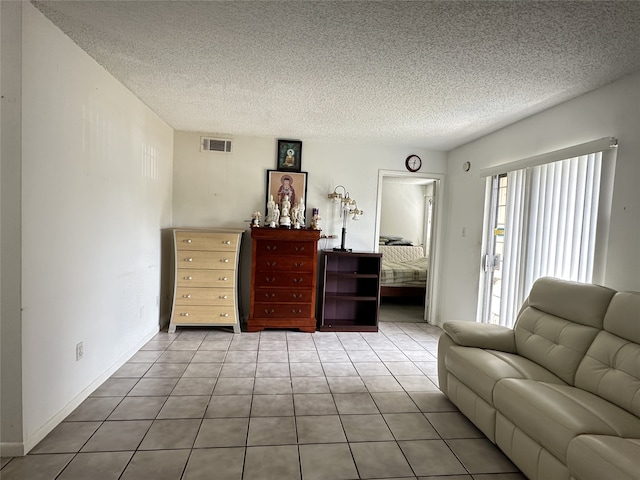 living area with tile patterned flooring, a textured ceiling, and visible vents