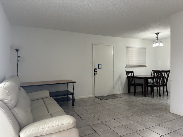 living area with light tile patterned floors, baseboards, a textured ceiling, and a chandelier