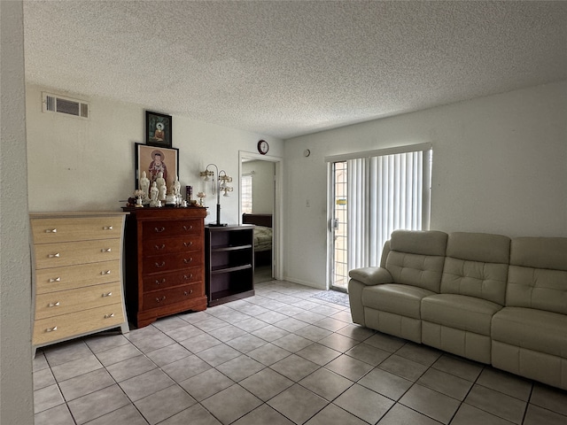 living room with visible vents, a textured ceiling, and light tile patterned floors
