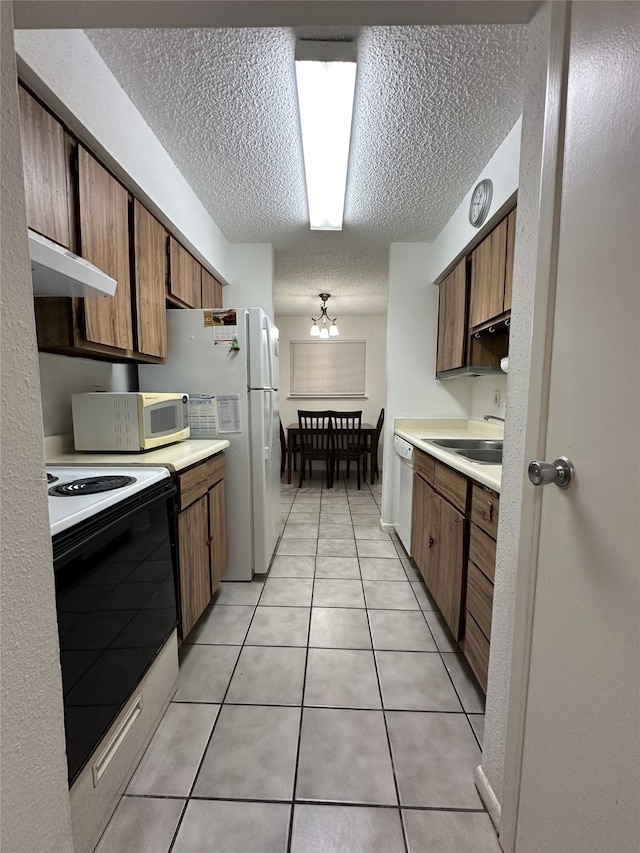 kitchen featuring light countertops, under cabinet range hood, white appliances, and a textured ceiling