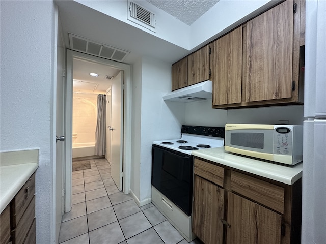kitchen with visible vents, electric stove, under cabinet range hood, and white microwave