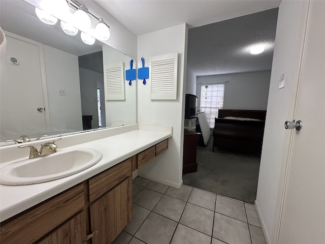 ensuite bathroom featuring vanity, baseboards, connected bathroom, a textured ceiling, and tile patterned floors