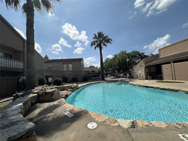 community pool with a patio and fence