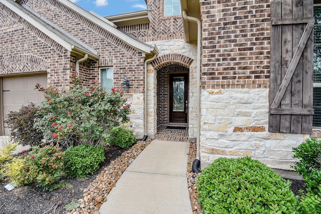 property entrance featuring brick siding, an attached garage, and stone siding