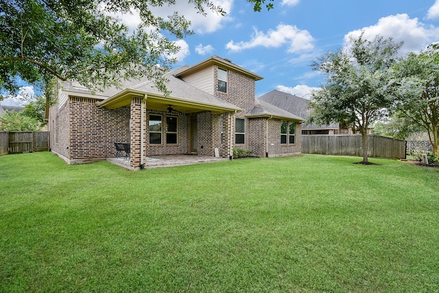 back of property with brick siding, ceiling fan, a fenced backyard, a patio, and a yard