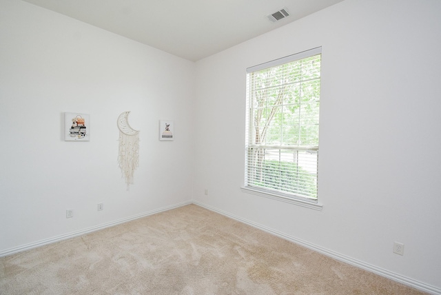carpeted spare room with baseboards, visible vents, and a healthy amount of sunlight