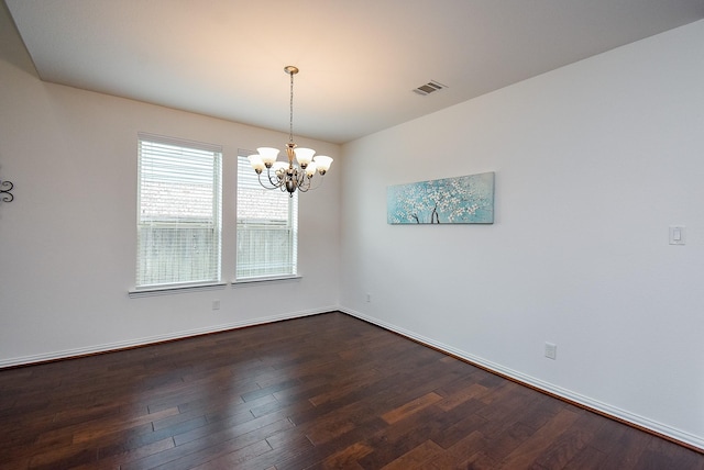 unfurnished room with an inviting chandelier, baseboards, dark wood-type flooring, and visible vents