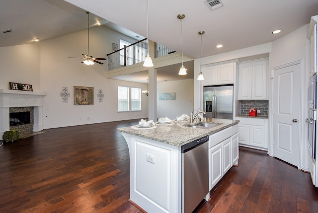 kitchen with ceiling fan, visible vents, a sink, open floor plan, and stainless steel appliances