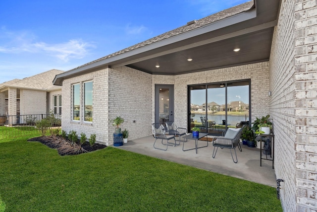 back of house with a lawn, fence, a patio area, and brick siding