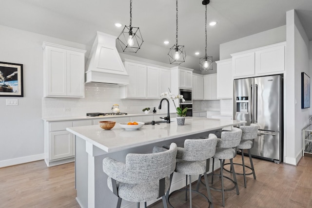 kitchen with appliances with stainless steel finishes, a sink, recessed lighting, custom range hood, and backsplash