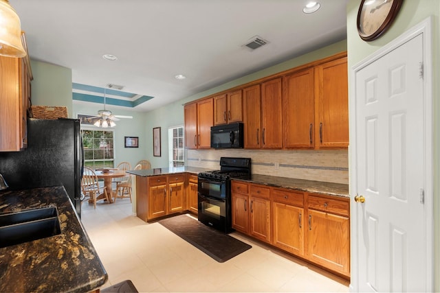 kitchen with brown cabinetry, visible vents, a sink, black appliances, and a peninsula