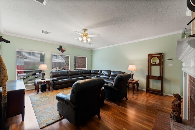 living area with a ceiling fan, visible vents, crown molding, a fireplace, and wood finished floors