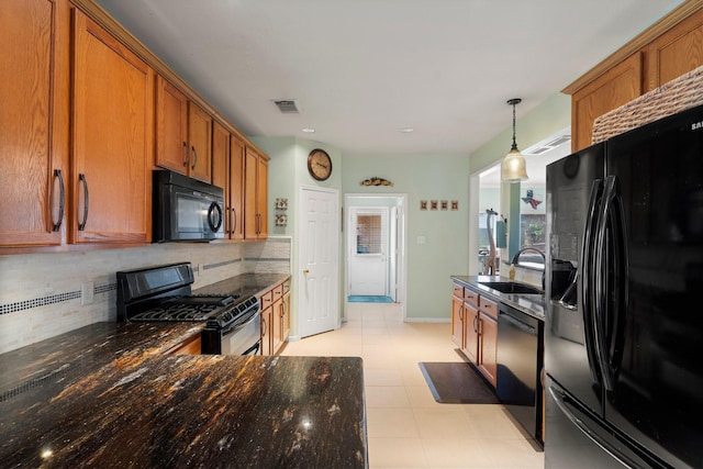 kitchen with decorative backsplash, visible vents, brown cabinets, a sink, and black appliances