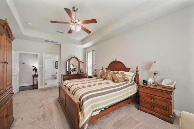 bedroom with light colored carpet, a ceiling fan, visible vents, and a raised ceiling