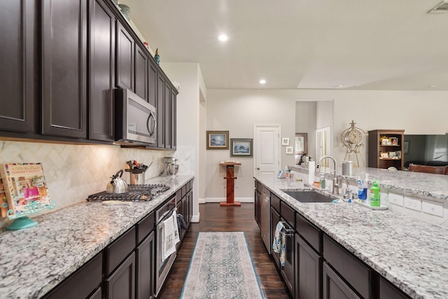 kitchen featuring decorative backsplash, baseboards, dark wood-type flooring, a sink, and appliances with stainless steel finishes