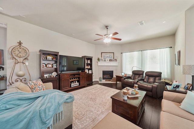 living area featuring visible vents, a ceiling fan, wood finished floors, and a tiled fireplace