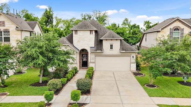 french country home featuring a shingled roof, stone siding, a front yard, and concrete driveway
