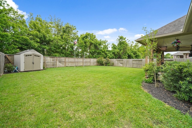 view of yard with a fenced backyard, an outbuilding, and a storage shed