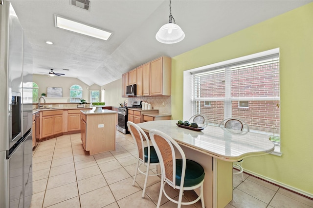 kitchen with light brown cabinetry, stainless steel appliances, lofted ceiling, and visible vents