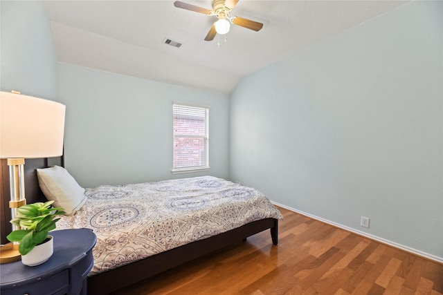 bedroom with visible vents, wood finished floors, baseboards, a ceiling fan, and vaulted ceiling