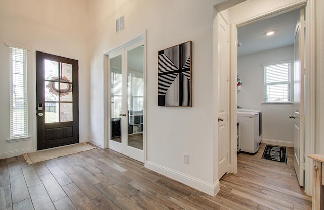 entrance foyer with baseboards, washer and clothes dryer, light wood-style flooring, and visible vents
