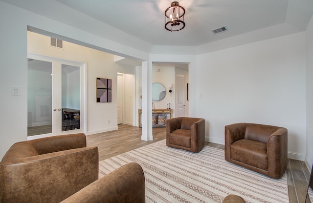 living room featuring baseboards, french doors, light wood-type flooring, and visible vents