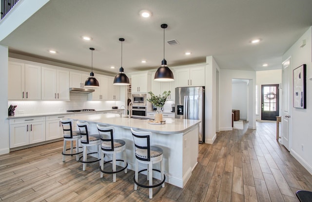 kitchen featuring light countertops, stainless steel appliances, light wood-style flooring, and white cabinetry