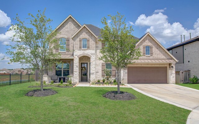 french country home with a standing seam roof, fence, concrete driveway, and stone siding