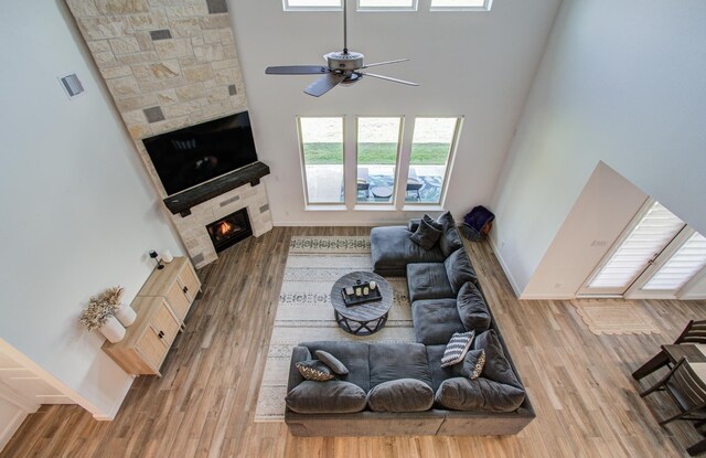 19018 Valentine Padlock Cir, Tomball, TX 77377 - living area with a stone fireplace, a ceiling fan, wood finished floors, a high ceiling, and baseboards